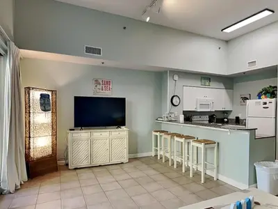 a kitchen with a bar with stools and a tv at Shores of Panama #109 in Panama City Beach