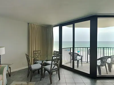 a living room with a table and chairs and a balcony at Sunbird Beach Resort #604 East in Panama City Beach