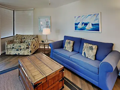a living room with a blue couch and a coffee table at Sunbird Beach Resort #712 East in Panama City Beach