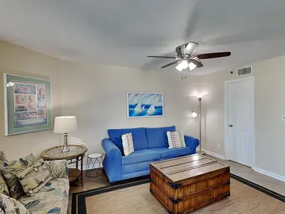 a living room with a blue couch and a ceiling fan at Sunbird Beach Resort #712 East in Panama City Beach