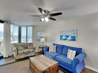 a living room with a blue couch and a ceiling fan at Sunbird Beach Resort #712 East in Panama City Beach