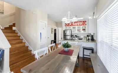 a kitchen and living room with a wooden table and a counter at Seashell Castle by Oversee 30A in Santa Rosa Beach