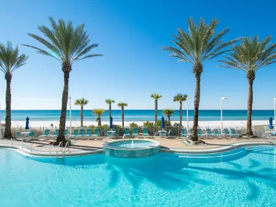 a pool with palm trees and the beach at Boardwalk #1008 in Panama City Beach