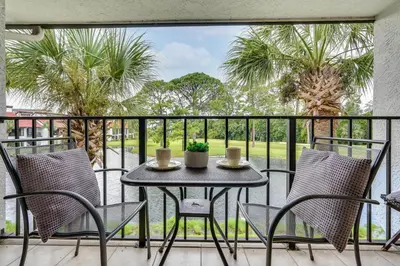 a patio with a table and chairs on a balcony at Pool and Beach Trolley Access PCB Resort Condo! in Panama City Beach