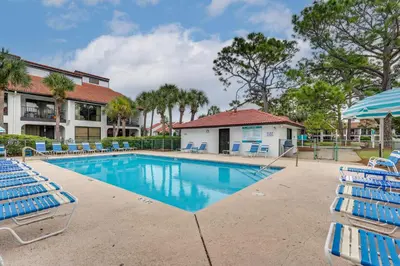 a swimming pool with lounge chairs and an umbrella at Pool and Beach Trolley Access PCB Resort Condo! in Panama City Beach