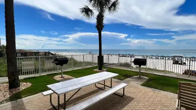 a white bench and a palm tree near the beach at Tropic Winds 2001 in Panama City Beach