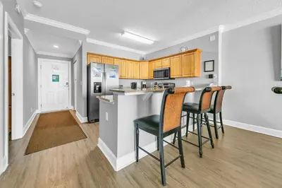 a kitchen with a bar with chairs and a counter top at Emerald Isle 2305 in Panama City Beach