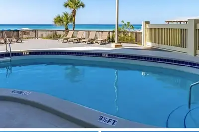 a swimming pool with the beach in the background at Ocean Front Beach Condo in Panama City Beach