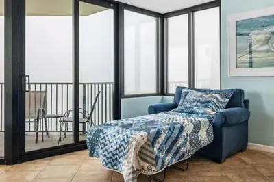a bedroom with a blue chair and a bed at Ocean Front Beach Condo in Panama City Beach
