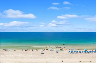 a group of people on a beach with the ocean at The Summit 828 in Panama City Beach