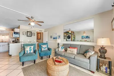 a living room with a couch and chairs and a kitchen at The Summit 828 in Panama City Beach