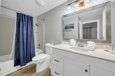 a bathroom with a sink and a toilet and a mirror at Ocean Villa 1803 in Panama City Beach