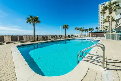 a large swimming pool with palm trees and a building at Ocean Villa 1803 in Panama City Beach
