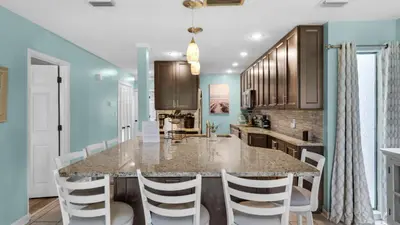 a kitchen with a large kitchen island with white chairs at Edgewater Golf Villa 707 in Panama City Beach