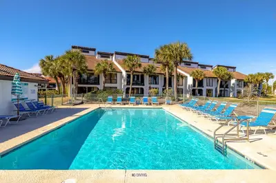 a swimming pool with chairs and a hotel at Edgewater Golf Villa 707 in Panama City Beach