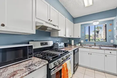a kitchen with white cabinets and a stove top oven at Panama City Beach Oasis in Panama City Beach