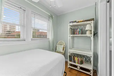 a white bedroom with a bed and a book shelf at Gulf Highlands #222 in Panama City Beach