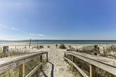 a wooden bench on a sandy beach near the ocean at Resort-Style PCB Townhome Beach Access and Pools! in Panama City Beach