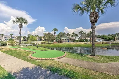 a golf course with a pond and palm trees at Resort-Style PCB Townhome Beach Access and Pools! in Panama City Beach