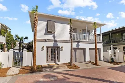 a white house with palm trees in front of it at 30A Beach Villa Steps to Beach Dog Friendly with Peloton and Bikes in Rosemary Beach