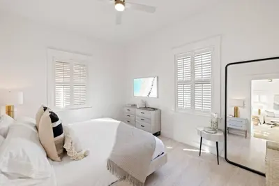 a white bedroom with a bed and a dresser and windows at 30A Beach Villa Steps to Beach Dog Friendly with Peloton and Bikes in Rosemary Beach
