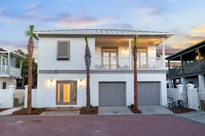 a white house with palm trees in front of it at 30A Beach Villa Steps to Beach Dog Friendly with Peloton and Bikes in Rosemary Beach