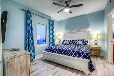 a blue bedroom with a bed and a ceiling fan at Laketown Wharf 1135 NEW in Panama City Beach