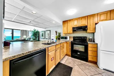 a kitchen with wooden cabinets and black appliances at Edgewater Tower 3-1104 in Panama City Beach