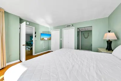 a large white bed in a room with green walls at Edgewater Tower 3-1104 in Panama City Beach