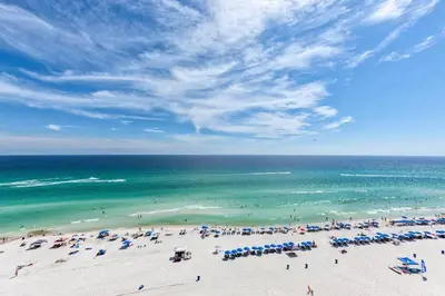a beach with a lot of umbrellas and the ocean at Edgewater Tower 3-1104 in Panama City Beach