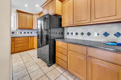a kitchen with wooden cabinets and a black refrigerator at Sunset Breeze in Panama City Beach