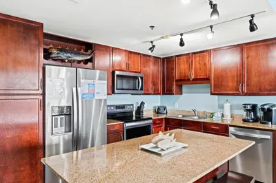 a kitchen with wooden cabinets and a stainless steel refrigerator at Blue Turtle at Laketown in Panama City Beach