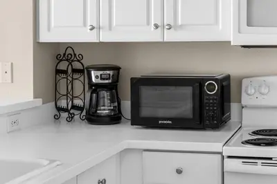 a kitchen counter with a microwave and a coffee maker at Beachfront Retreat! Family Friendly 1BD Getaway! by Dolce Vita Getaways PCB! in Panama City Beach