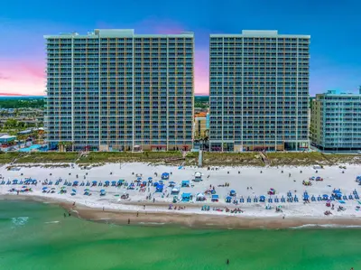 a beach with umbrellas and people on it with buildings at Beachfront Retreat! Family Friendly 1BD Getaway! by Dolce Vita Getaways PCB! in Panama City Beach