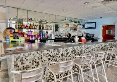 a bar with white chairs in a restaurant at Beachfront Retreat! Family Friendly 1BD Getaway! by Dolce Vita Getaways PCB! in Panama City Beach