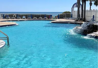 a swimming pool with blue water in front of the ocean at Beachfront Retreat! Family Friendly 1BD Getaway! by Dolce Vita Getaways PCB! in Panama City Beach