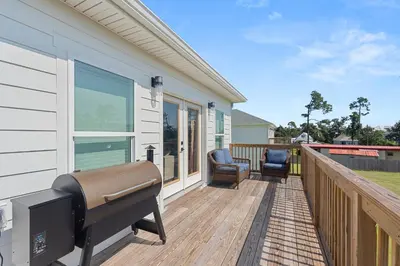 a deck with a grill and chairs on a house at Luxury Retreat near St. Andrews in Panama City Beach