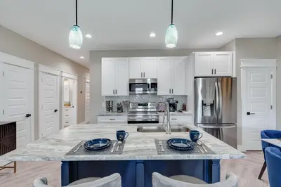 a kitchen with white cabinets and a marble counter top at Luxury Retreat near St. Andrews in Panama City Beach
