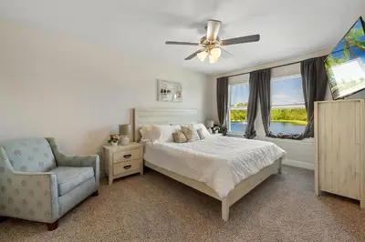 a bedroom with a bed and a chair and a ceiling fan at Florida Knights by the Sea in Panama City Beach