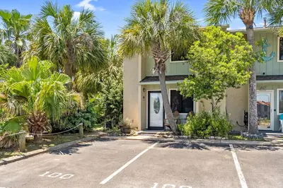 a parking lot in front of a house with palm trees at Coconut Cottage in Panama City Beach