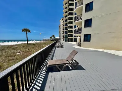 a bench on a boardwalk next to the beach at Sunbird Resort! Stunning Beach and Ocean Views! by Dolce Vita Getaways PCB in Panama City Beach