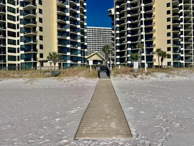 a boardwalk in the sand on a beach with buildings at Sunbird Resort! Stunning Beach and Ocean Views! by Dolce Vita Getaways PCB in Panama City Beach