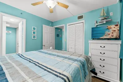a blue bedroom with a bed and a ceiling fan at Sunbird Resort! Stunning Beach and Ocean Views! by Dolce Vita Getaways PCB in Panama City Beach