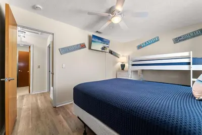 a bedroom with a blue bed and a ceiling fan at Charming Townhouse in Gulf Highland Beach Resort! Amenities Galore in Panama City Beach