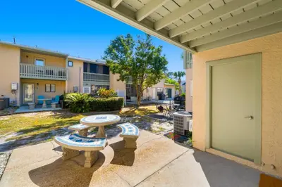 a patio with a table and benches in front of a building at Charming Townhouse in Gulf Highland Beach Resort! Amenities Galore in Panama City Beach