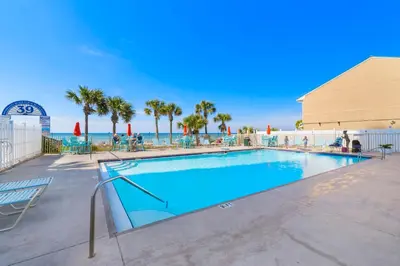 a swimming pool at a resort with palm trees at Charming Townhouse in Gulf Highland Beach Resort! Amenities Galore in Panama City Beach