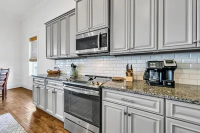 a kitchen with white cabinets and a stove top oven at Gathering Thyme in Santa Rosa Beach
