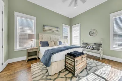 a bedroom with a bed and a table and windows at Gathering Thyme in Santa Rosa Beach
