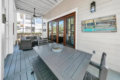 a porch with a wooden table on a house at Gathering Thyme in Santa Rosa Beach