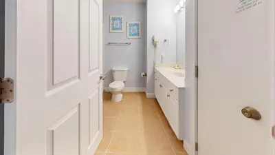 a white bathroom with a toilet and a sink at Tidewater 1616 in Panama City Beach